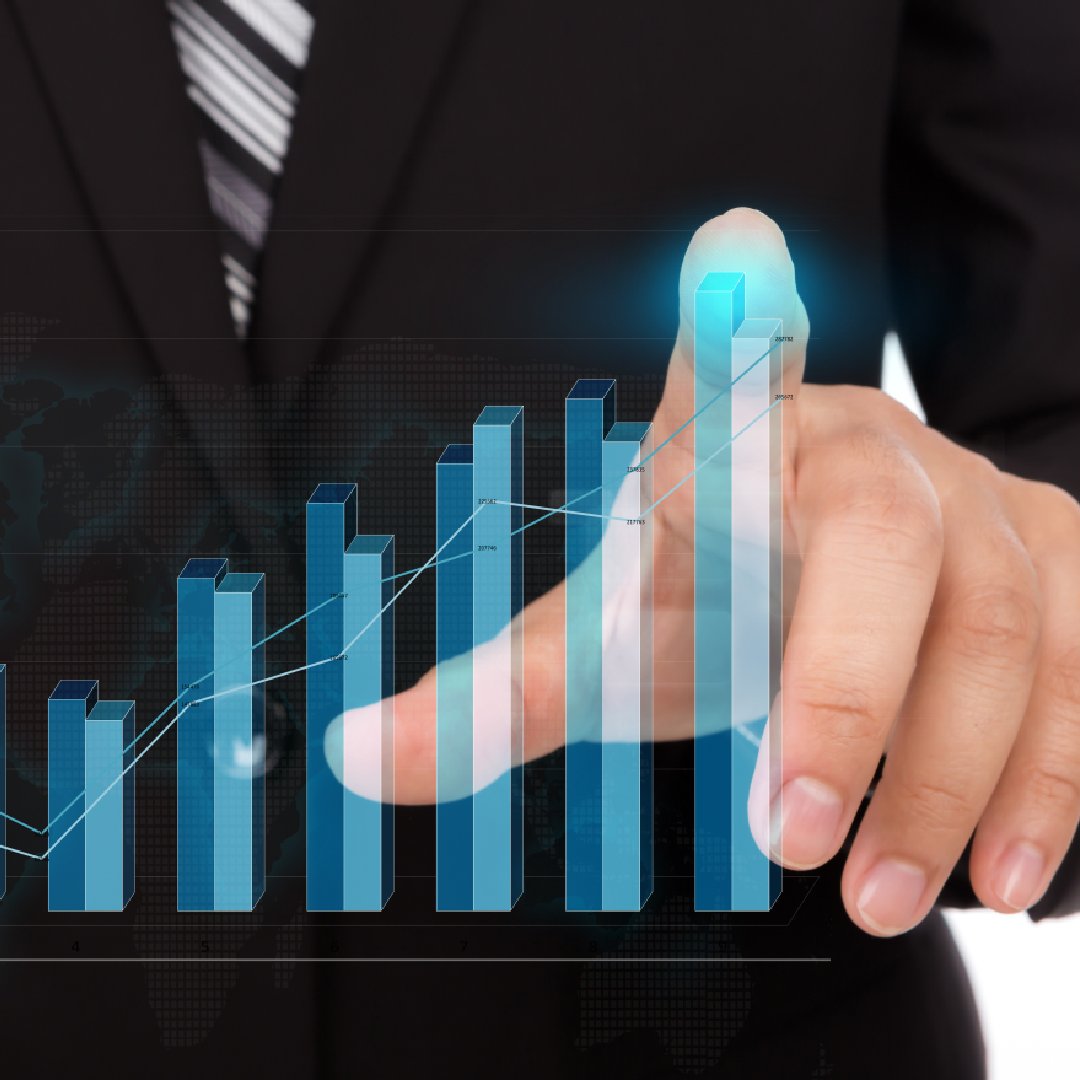 A person in a suit touches a glowing digital bar chart with a line graph overlay, suggesting data analysis, growth, and success in business.