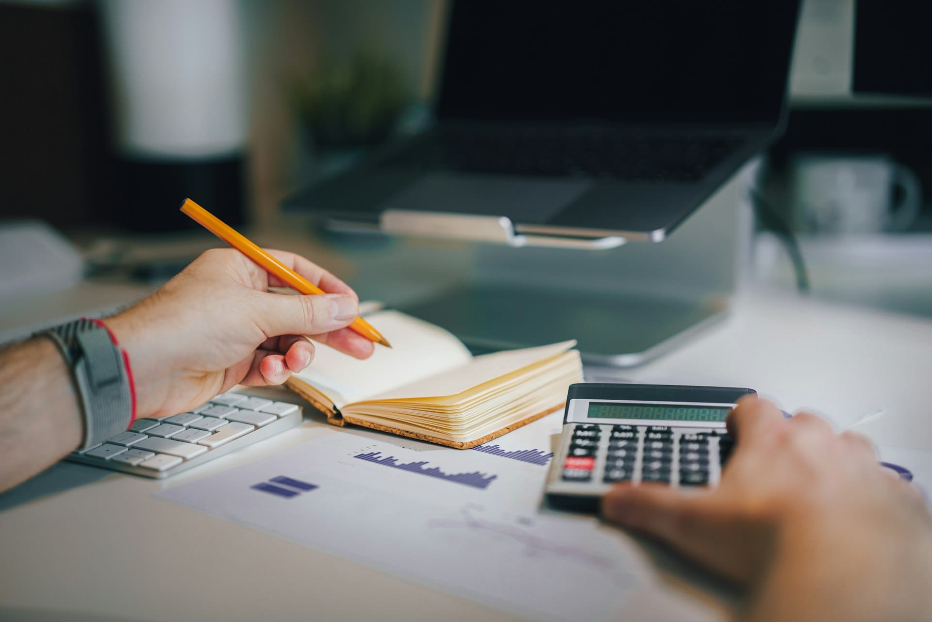 Reviewing financial projections with a calculator and notebook at a desk